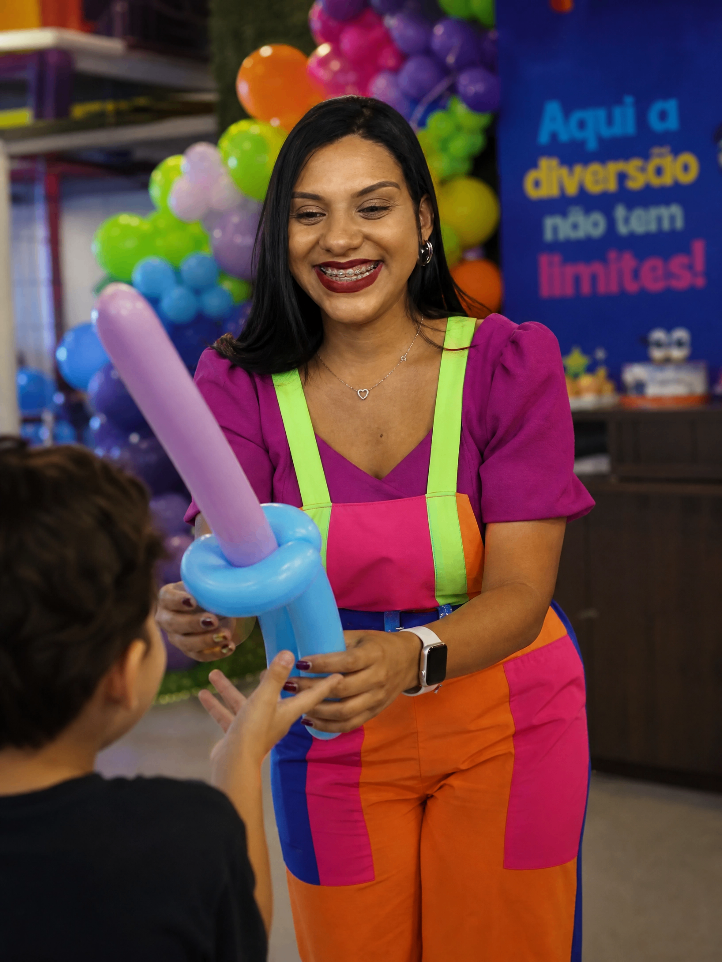 Recreadora entregando escultura de balão para criança